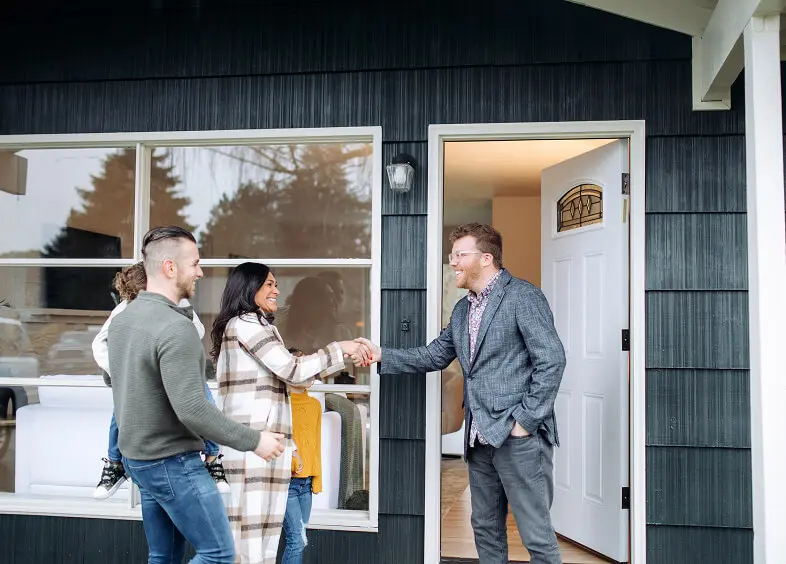 Family greeting man at house entrance.