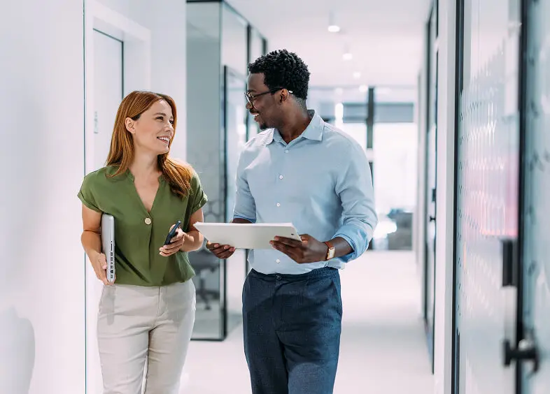 Two colleagues walking and talking in office.
